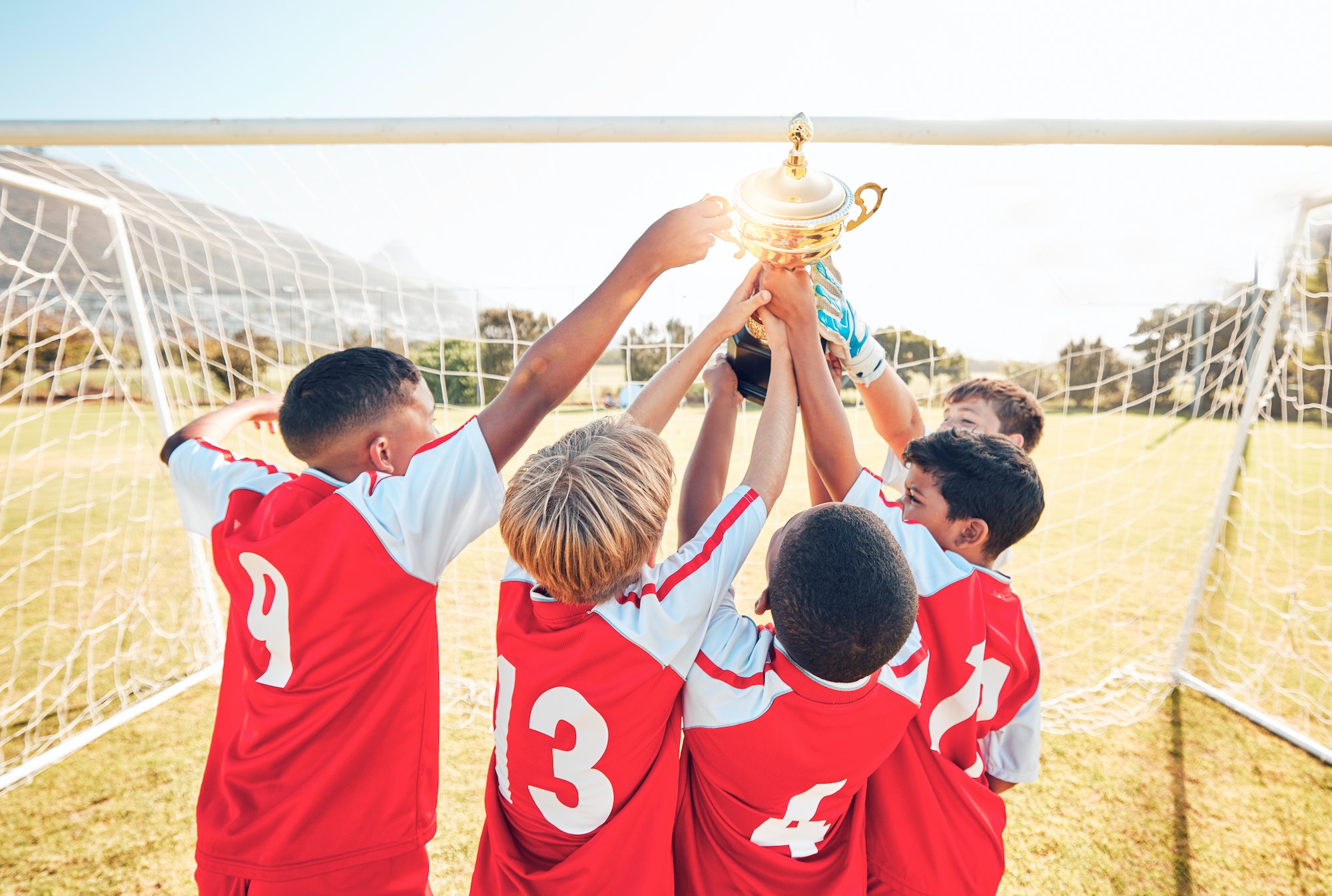 Children, winner and team soccer with trophy celebrating victory, achievement or match on the field